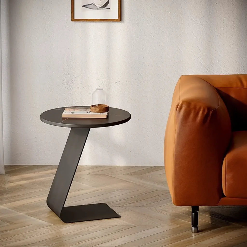 Table d'appoint ronde en marbre avec base en métal noir et forme en C, idéale pour un canapé.