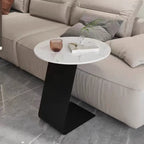 Table d'appoint ronde en marbre avec base en métal noir et forme en C, idéale pour un canapé.