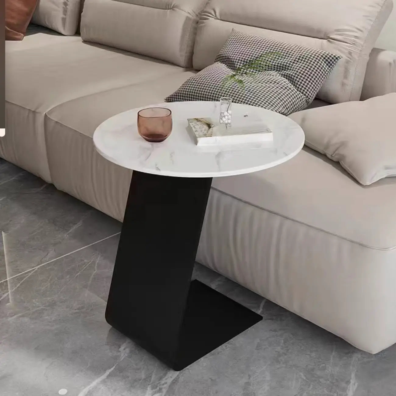 Table d'appoint ronde en marbre avec base en métal noir et forme en C, idéale pour un canapé.
