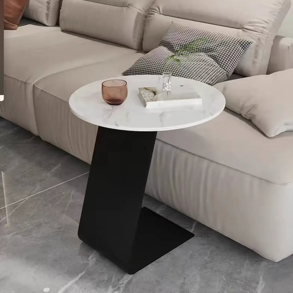 Table d'appoint ronde en marbre avec base en métal noir et forme en C, idéale pour un canapé.