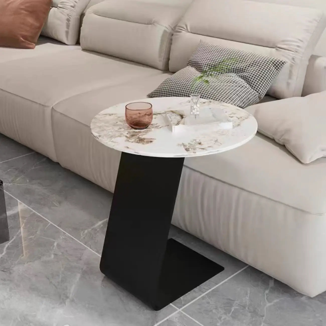 Table d'appoint ronde en marbre avec base en métal noir et forme en C, idéale pour un canapé.