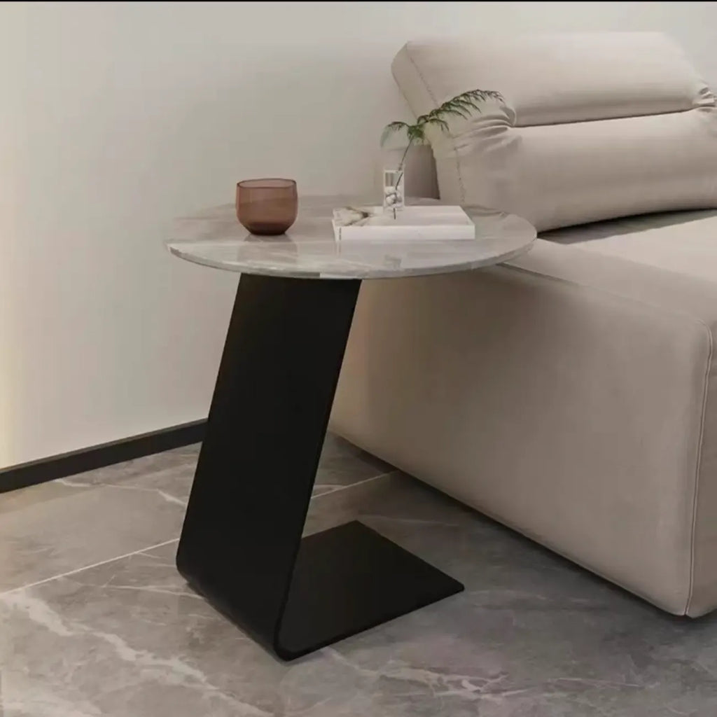 Table d'appoint ronde en marbre avec base en métal noir et forme en C, idéale pour un canapé.