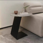 Table d'appoint ronde en marbre avec base en métal noir et forme en C, idéale pour un canapé.