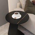 Table d'appoint ronde en marbre avec base en métal noir et forme en C, idéale pour un canapé.