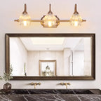 Applique murale moderne à trois lampes en laiton avec globe, à placer au-dessus du miroir.