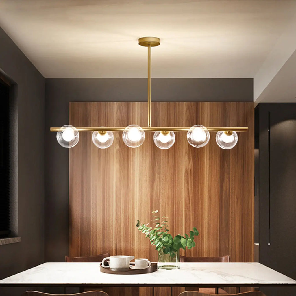 Applique murale linéaire dorée pour îlot central, avec 6 abat-jour en verre transparent.