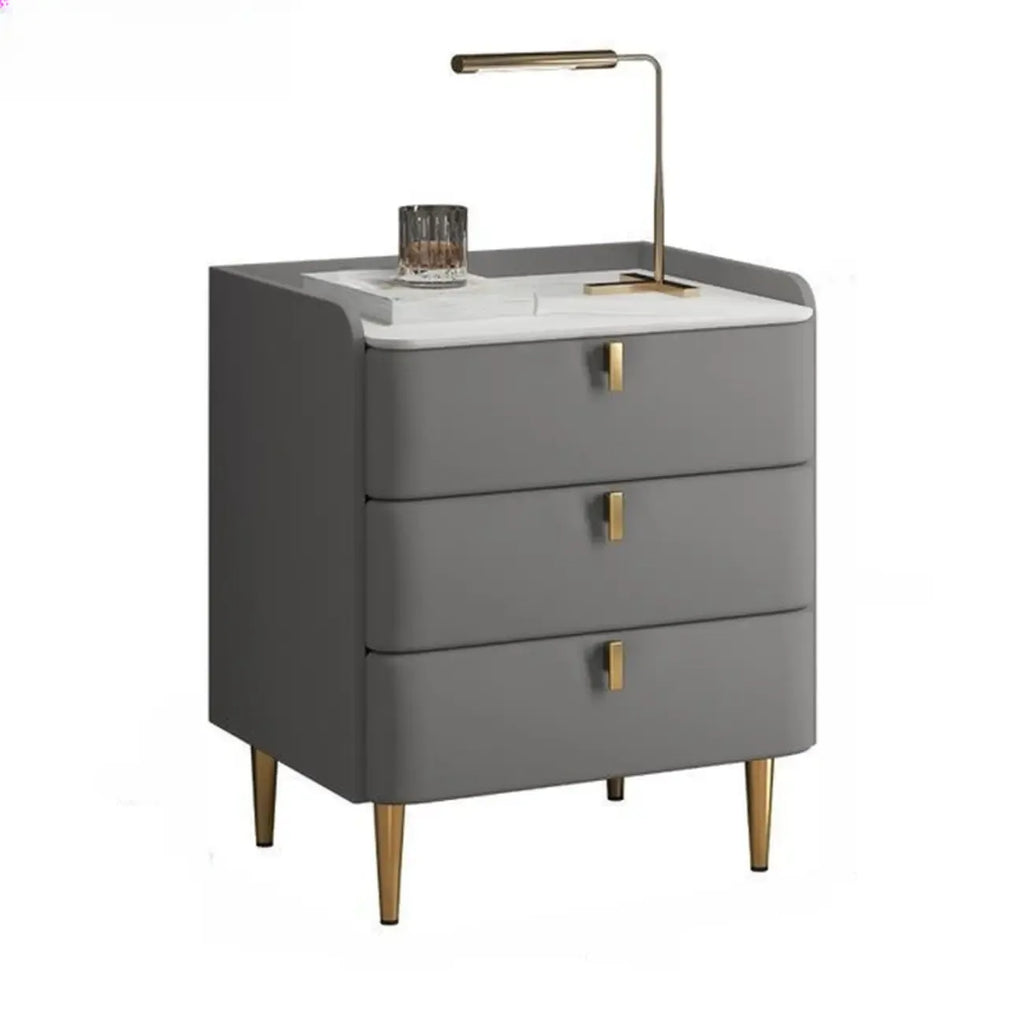 Table de chevet moderne à 3 tiroirs avec plateau en pierre, finitions dorées et revêtement en cuir.
