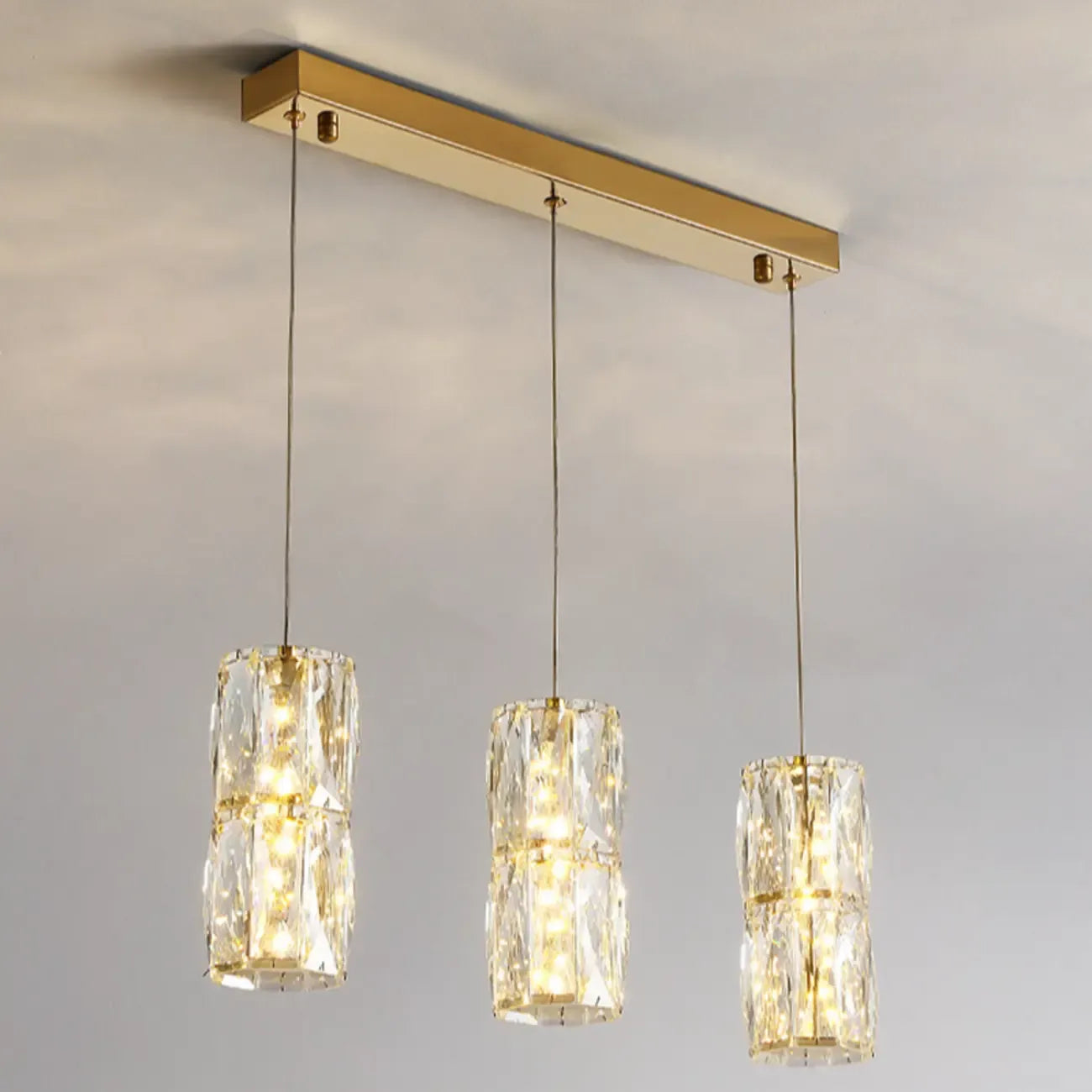 Suspension cylindrique en cristal pour îlot de cuisine, éclairage LED à intensité variable.
