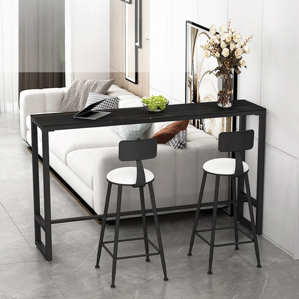 Table de bar moderne avec plateau en pierre noire, piètement à tréteaux et repose-pieds