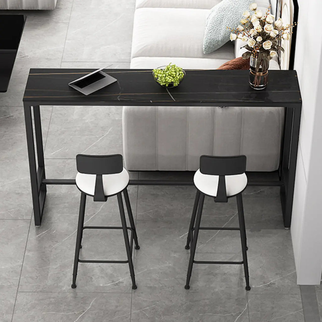 Table de bar moderne avec plateau en pierre noire, piètement à tréteaux et repose-pieds