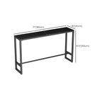 Table de bar moderne avec plateau en pierre noire, piètement à tréteaux et repose-pieds
