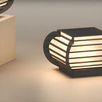 Poteau lumineux extérieur en métal en forme de tambour avec capuchon de protection pour grille.