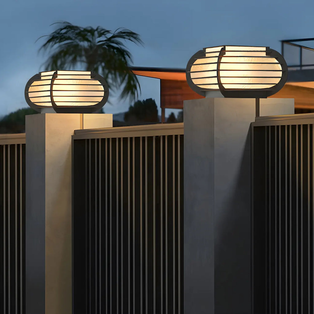 Poteau lumineux extérieur en métal en forme de tambour avec capuchon de protection pour grille.