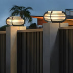 Poteau lumineux extérieur en métal en forme de tambour avec capuchon de protection pour grille.